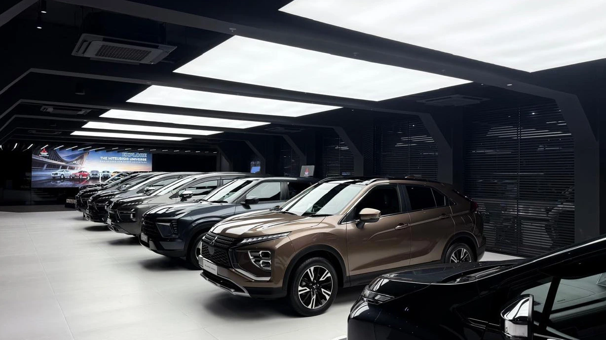 Photograph of Mitsubishi vehicles lined up under luminous ceiling panels.