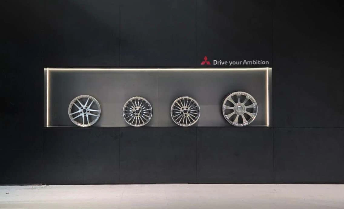 Photograph of four alloy wheels displayed in a recessed illuminated wall niche.
